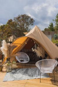 2 sedie e una tenda su una terrazza in legno di AKOA GLAMPING Eco-Luxury Hotel a Guarne