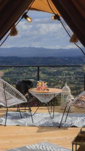 un tavolo e sedie su un balcone con vista di AKOA GLAMPING Eco-Luxury Hotel a Guarne