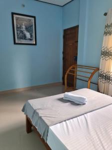 ein blaues Zimmer mit einem Bett mit einer weißen Decke in der Unterkunft Nalluran illam - family room in Jaffna