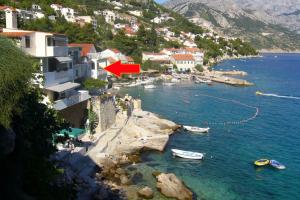 a group of buildings and boats in the water at Apartments by the sea Pisak, Omis - 1003 in Mimice +8 photos