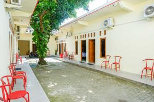 a courtyard of a building with red chairs and tables at RedDoorz @ Umbul Ponggok Waterpark Klaten in Klaten