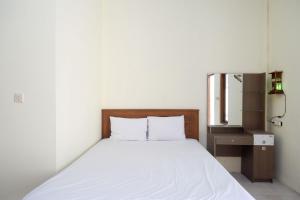 a bedroom with a white bed and a mirror at RedDoorz @ Umbul Ponggok Waterpark Klaten in Klaten