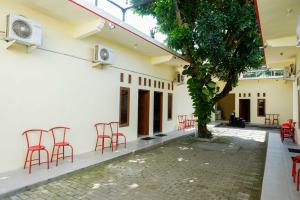 a courtyard with red chairs and a tree at RedDoorz @ Umbul Ponggok Waterpark Klaten in Klaten