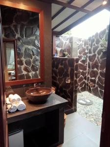 baño con lavabo y pared de piedra en BINTANG MUNDUK en Munduk