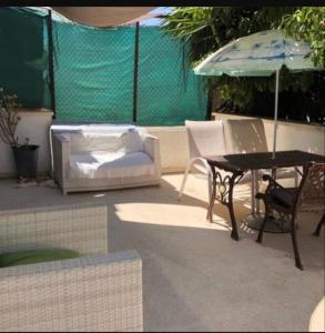 un patio con mesa, sillas y sombrilla en Golden sunshine, en Paralimni