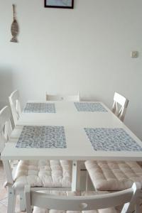 einen weißen Tisch mit weißen Stühlen und einer weißen Wand in der Unterkunft Apartments by the sea Milna, Brac - 18743 in Milna