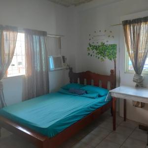 um quarto com uma cama com lençóis azuis e uma janela em Pier La Casa Homestay Building em Surigao