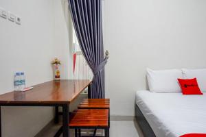 Cette chambre comprend un bureau, un lit, un lit et une fenêtre. dans l'établissement RedDoorz Syariah near RS Mitra Keluarga Tegal, à Tegal