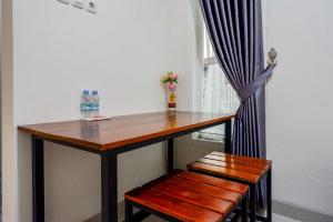 a wooden table with a bench and a window at RedDoorz Syariah near RS Mitra Keluarga Tegal in Tegal