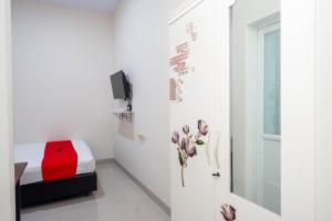 biały pokój z łóżkiem i oknem w obiekcie RedDoorz Syariah near RS Mitra Keluarga Tegal w mieście Tegal
