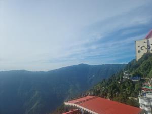 a view of a mountain valley with a building and mountains at Kheychun homestay in Darjeeling