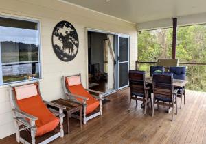 un porche cubierto con mesa y sillas en Water View Country Cottage, en Yandina Creek