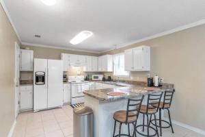 a kitchen with white cabinets and a island with bar stools at Seaside Sanctuary close to Navarre Beach! in Navarre