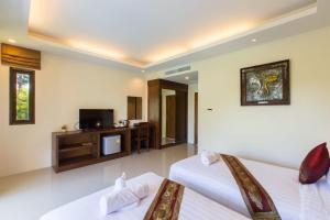 a hotel room with two beds and a television at The Casita Phuket (SHA+) in Ban Bo Sai Klang