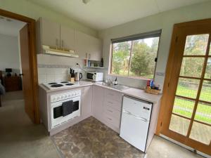 eine Küche mit einem weißen Herd oberer Ofen neben einem Fenster in der Unterkunft Richo’s Retreat, 1 bed unit near Great Ocean Road in Cobden