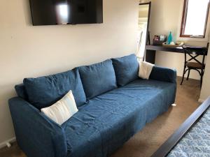 un sofá azul sentado en una sala de estar en 5 Star Room with own Bathroom - Singles, Couples, Families or Executives, en Glen Waverley