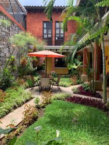 un patio con mesa y sombrilla frente a un edificio en Casa El Conquistador, en Antigua Guatemala