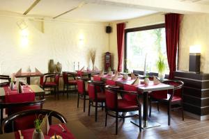 un restaurante con sillas y mesas rojas y una ventana en Hotel Altastenberg, en Winterberg