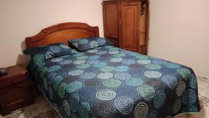 ein Bett mit einer blauen Bettdecke und Kissen darauf in der Unterkunft HOTEL GALERAS in Pasto