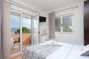 a white bedroom with a bed and a balcony at Apartments with a parking space Okrug Donji, Ciovo - 18796 in Okrug Gornji