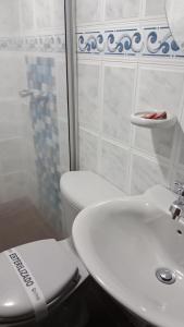 a white bathroom with a toilet and a sink at HOTEL GALERAS in Pasto