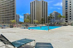 a swimming pool with two chairs and buildings at Waikiki Banyan #2601-T2 in Honolulu