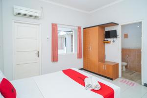ein weißes Schlafzimmer mit einem Bett und einem Badezimmer in der Unterkunft RedDoorz near Rumah Sakit Baptis Kediri in Kediri