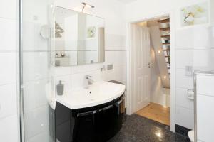 een witte badkamer met een wastafel en een spiegel bij Haus Traavmünn in Travemünde