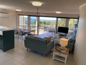 uma sala de estar com um sofá e uma mesa com uma televisão em Belvedere Apartments em Caloundra