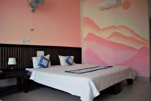 1 dormitorio con 1 cama grande y pared de color rosa en Đồi Dừa Homestay, en Phan Thiet