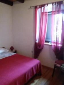 Schlafzimmer mit einem Bett und einem Fenster mit rosa Vorhängen in der Unterkunft Holiday house with a parking space Olib - 18805 in Olib