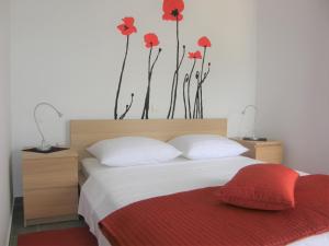 sypialnia z łóżkiem z czerwonymi kwiatami na ścianie w obiekcie Apartments with a parking space Baska, Krk - 18871 w Bašce