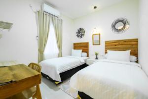 a bedroom with two beds and a desk and a desk at Siji Plemburan Vacation Home in Kejayan