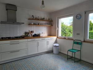 uma cozinha com armários brancos e uma cadeira verde em Haus Sonnenlicht. Idylle am Ratzeburger See! em Ratzeburg