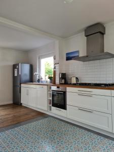 a kitchen with white cabinets and a black refrigerator at Haus Sonnenlicht. Idylle am Ratzeburger See! in Ratzeburg