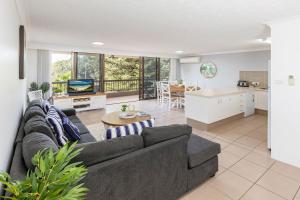 a living room with a gray couch and a kitchen at Pinnacle 202 in Forster