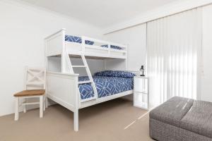 a white bedroom with a bunk bed with a ladder at Pinnacle 202 in Forster