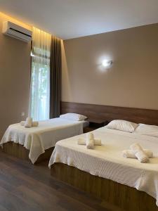 a bedroom with two beds with white sheets and a window at Villa Del Mar in Gonio