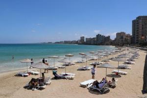 a group of people sitting on a beach with umbrellas at Secret Garden Guest House 02 in Famagusta
