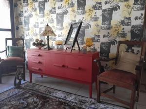 een rode dressoir in een kamer met een spiegel en 2 stoelen bij Goedehoop in Welkom