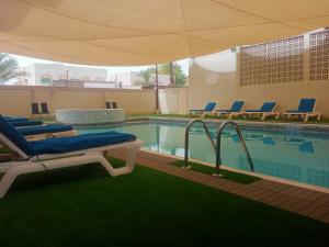 basen z leżakami i parasolem w obiekcie Oasis Hotel Apartment w mieście Ras al-Chajma