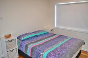 a bedroom with a bed with a colorful blanket at Three Fifty Four Straight St Hat Head in Hat Head