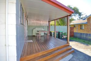 a wooden deck with a table on a house at Three Fifty Four Straight St Hat Head in Hat Head