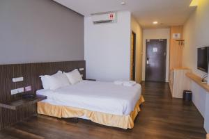 Roxy Hotel Serian في Serian: غرفه فندقيه سرير وتلفزيون