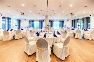 um salão de banquetes com mesas brancas e cadeiras brancas em Select Hotel A1 Bremen-Stuhr em Stuhr