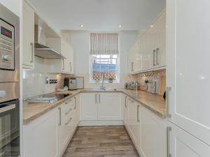 a white kitchen with white cabinets and a sink at Flat 4B in Chester