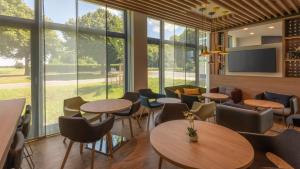ein Restaurant mit Tischen und Stühlen und großen Fenstern in der Unterkunft Holiday Inn Express - Krefeld - Dusseldorf, an IHG Hotel in Krefeld