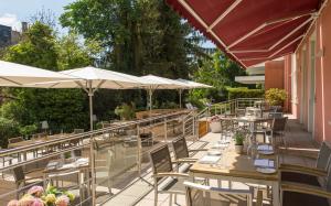a restaurant with tables and umbrellas on a patio at Hotel Oranien Wiesbaden in Wiesbaden