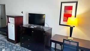 Habitación de hotel con TV y escritorio con lámpara. en Super Inn & Suites Philadelphia, en Filadelfia