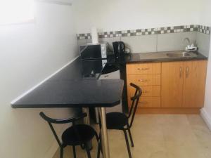 a kitchen with a black counter and two chairs at Gem Quays Waterfront in Knysna